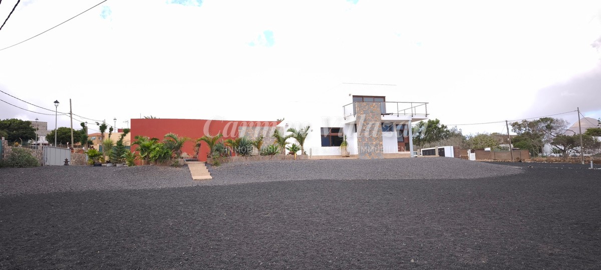 Panorámica desde otro angulo de la fachada principal con el terreno delante